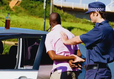 Police officer arresting a black American guy for DUI charges.