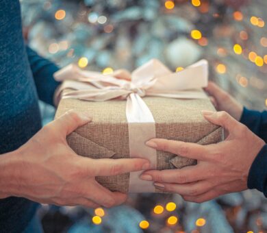 Hände überreichen Geschenk