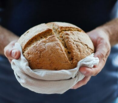 zwei Hände halten ein ganzes Brot