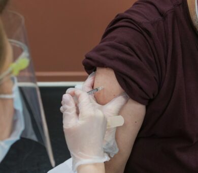 Ärztin setzt eine Spritze an einen Arm