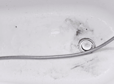 Bathtub overflow plate and trip lever drain stopper being inspected for a leak