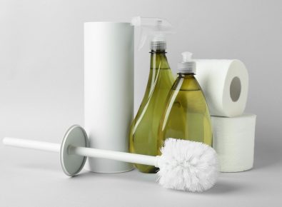 Flat-lay view of a toilet brush and drain cleaners on a neutral background.