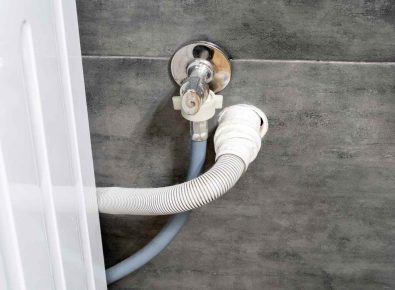 Washing machine drain hose connected to a standpipe behind a front-load washer.