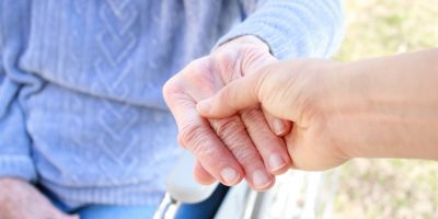 Eine Person im Rollstuhl greift eine andere Hand