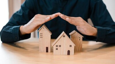 modele domu, bloku, mężczyzna ochrania złożonymi dłoniami