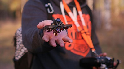 Man wearing goggles and holding mini drone