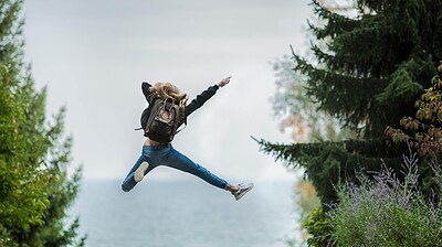 woman jumping wearing green backpack