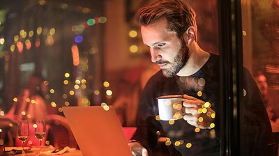 man holding mug in front of laptop