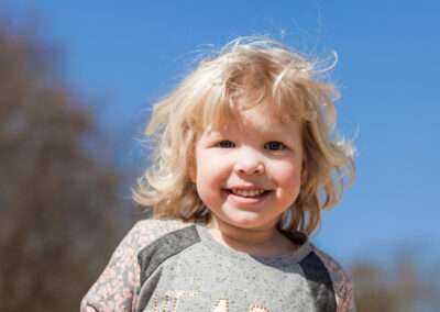 Een blij blond meisje tijdens een gezinsshoot in de duinen in Kijkduin