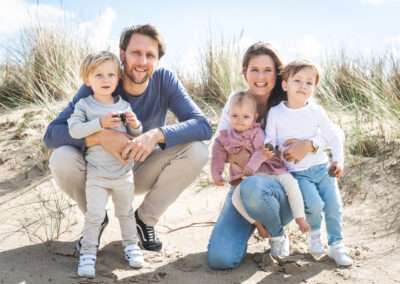 Papa, mama en hun drie jonge kinderen samen op de foto in de duinen van Den Haag