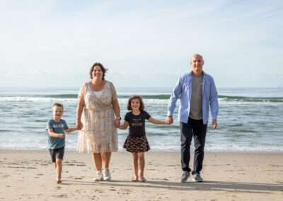 Gezin met twee kinderen loopt vanaf de zee naar de duinen, bij Kijkduin in Den Haag