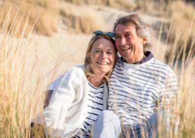 Ouder verliefd stel zit tussen het helmgras in de duinen van Zeeland