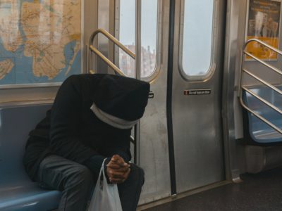man with head down sitting on a train