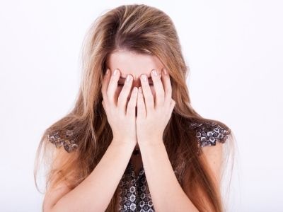 Ausgeprannt sein als Mutter, Frau hält sich die Hände vor das Gesicht