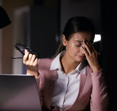 Woman tired of work Young businesswoman touching her head while sitting at her workplace with laptop she tired of her work at office