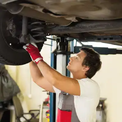 Mechanic working on Land Rover wheel area to diagnose and fix land rover air suspension problems