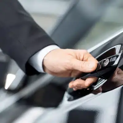Driver begins BMW servicing appointment by unlocking car door with key fob outside dealership today