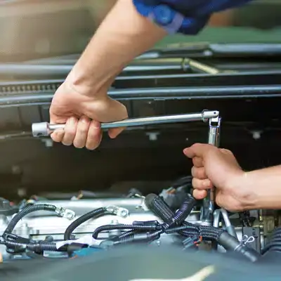 Mechanic completes BMW servicing by tightening engine component with ratchet tool inside open hood area