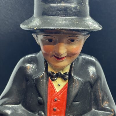 Mann mit rotem Regenschirm. Sehr große Spardose aus Keramik, polychrom bemalt. Wohl um 1930.