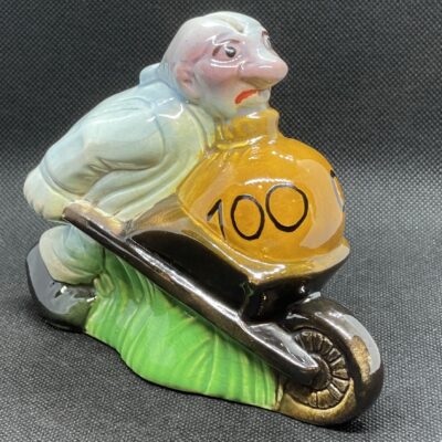 Esdève, Sarreguemines: Mann mit Schubkarre trägt sein Geld zur Bank. Keramische Spardose, ca. 1920