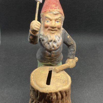Uralte Spardose um 1900. Zwerg mit Axt am Baumstumpf hackt Holz.