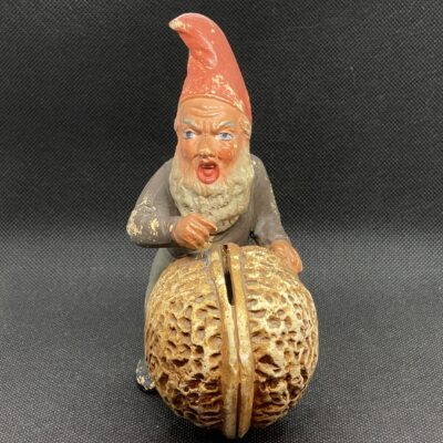 Grantiger Zwerg rollt Walnuss. Keramik-Spardose, Deutschland, um 1900.
