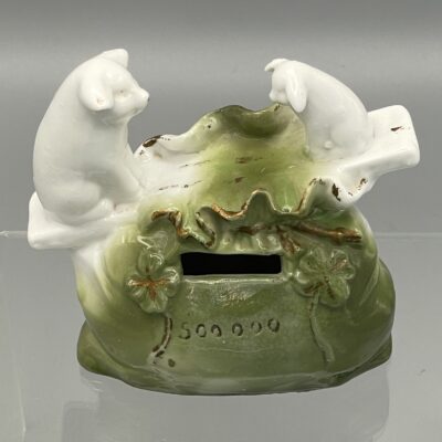 Spardose: Schweinchen balancieren auf Brett über Geldsack. Porzellan, Deutschland um 1900