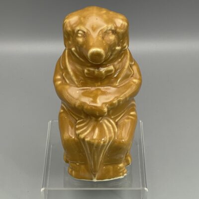 Sitzendes Schwein mit Schirm, Spardose aus hellbraun glasierter Keramik. Wohl St. Uze, um 1920