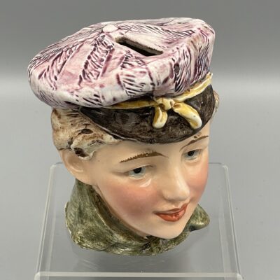 Sehr fein ausgeführte Keramik-Figur (Spardose) eines Jungen mit Mütze. Um 1920.