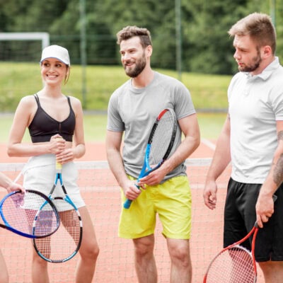Friends on the tennis court Group of friends having fun standing together with rackets on the tennis court