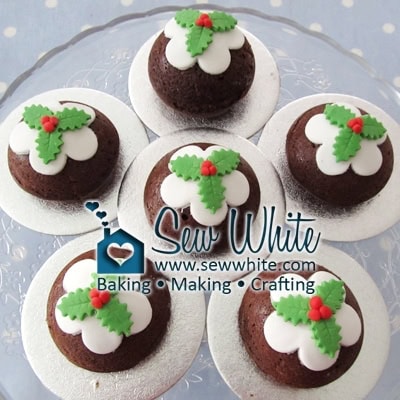 little Christmas Pudding Cakes topped with white icing and cut out holly leaves