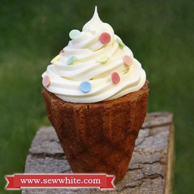 A golden brown ice cream cone cake decorated with buttercream and sprinkles