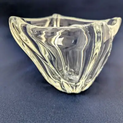 Coupelle vide-poche en cristal Daum France de forme organique, design moderne épuré avec signature gravée, objet de collection en cristal transparent.