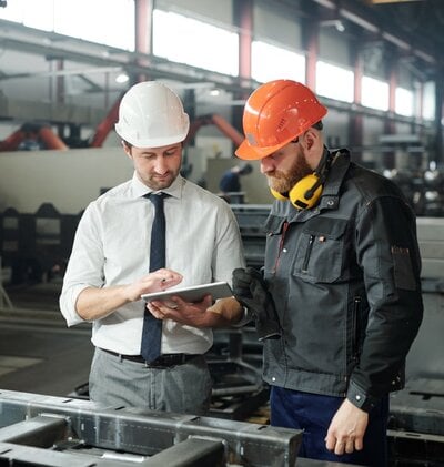 two workers checking a tablet on a worksite