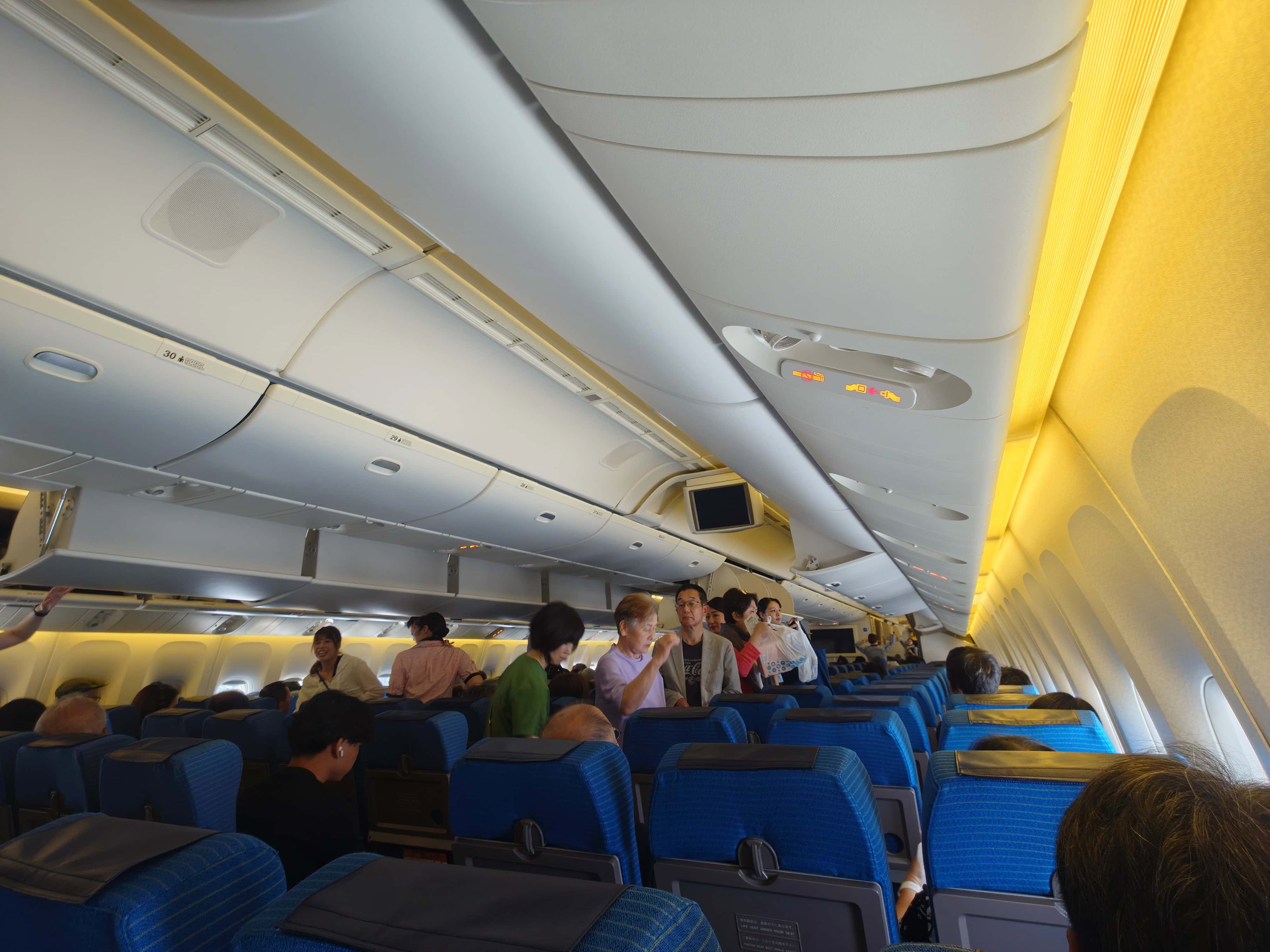 搭乗中の客室、黄色いムード照明の中3列シートは空席が目立つ
