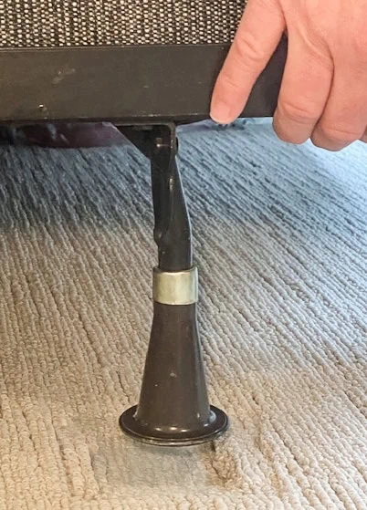 Before image of a metal bed frame leg being lifted up to install bedboots