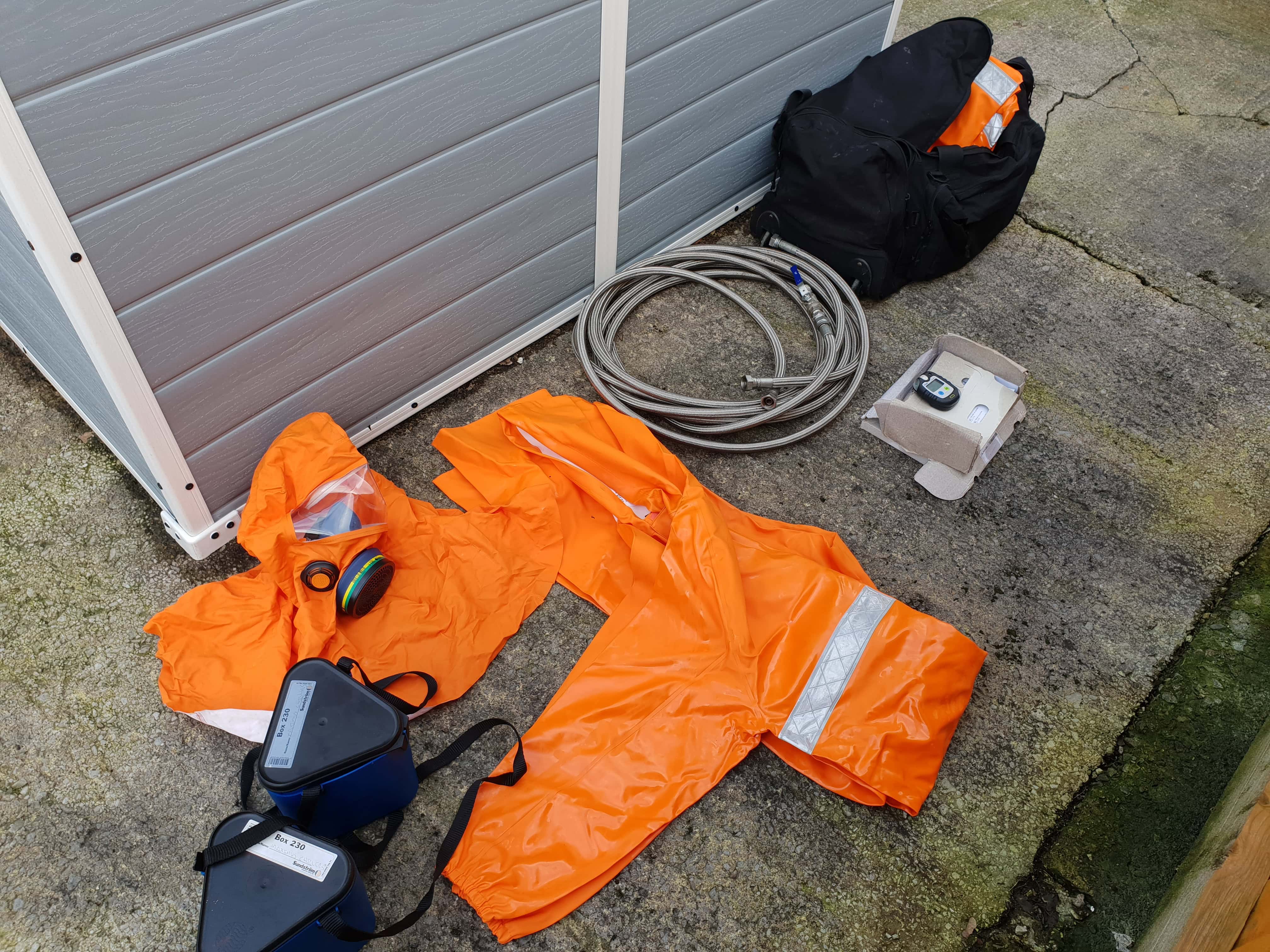 Orange chemical suit and charging hose for ammonia chiller service maintenance and repair