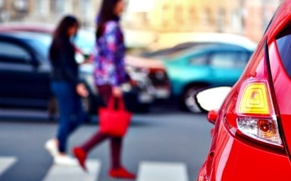 Woman crossing street in front of car.