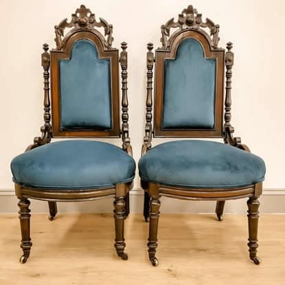 Stylish blue velvet upholstered antique dining chairs with ornate carved wood frames. Perfect for luxurious interiors.