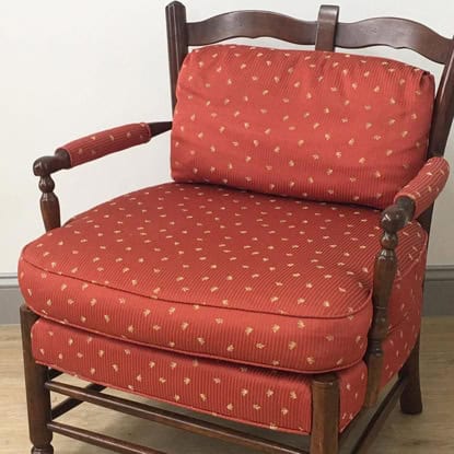 Elegant red armchair with gold dotted upholstery, wooden frame, comfortable cushion, and decorative armrests.