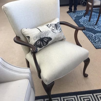 Armchair with butterfly pillow, wooden frame, classic indoor furniture, comfortable seating.