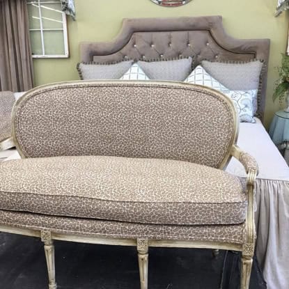 Cream and beige patterned loveseat with elegant wooden frame.