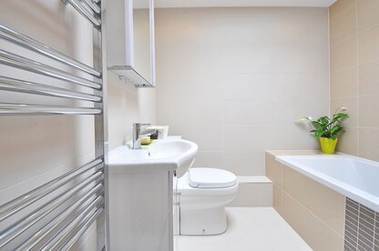 Bathroom suite. Newly installed towel radiator. Toilet and bath in background.