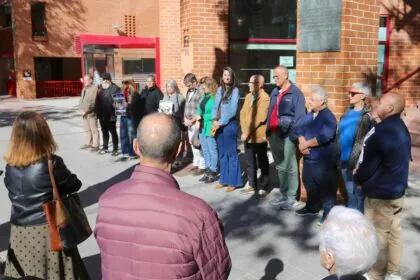 Grupo de personas en el exterior de un edificio, guardando un minuto de silencio, en Coslada (Madrid).