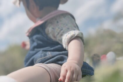 芝生の上にピンク色の帽子を被った女の子が座っている
