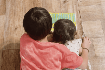 兄と妹が床に寝転んで絵本を読んでいる