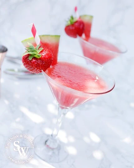 Watermelon and Strawberry Martini on a marble background in the sunshine decorated with watermelon slice and strawberry