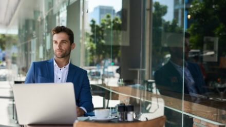 A young professional works on his laptop in an outdoor space at 1000 Social, a luxury office building that centers work around access to modern amenities and Raleigh park space.