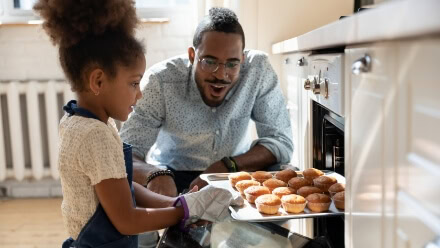 A father and daughter remove a tray of cookies from the oven in their luxury Raleigh apartment.