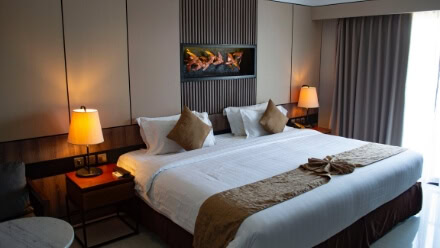 A large bed in a modern, well-appointed bedroom with a built in fireplace in a luxury Raleigh apartment